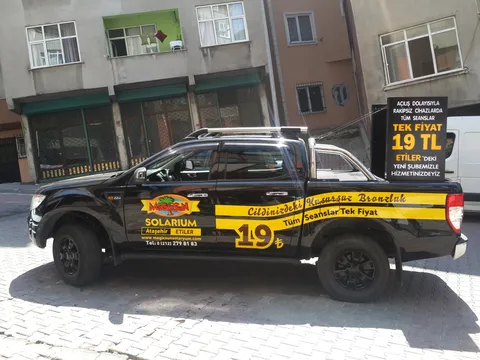 Magic Sun Solarium tanıtım aracı (Ford Ranger) tam araç giydirme - siyah/sarı folyo kaplama ve mobil reklam panosu, yan görünüm.