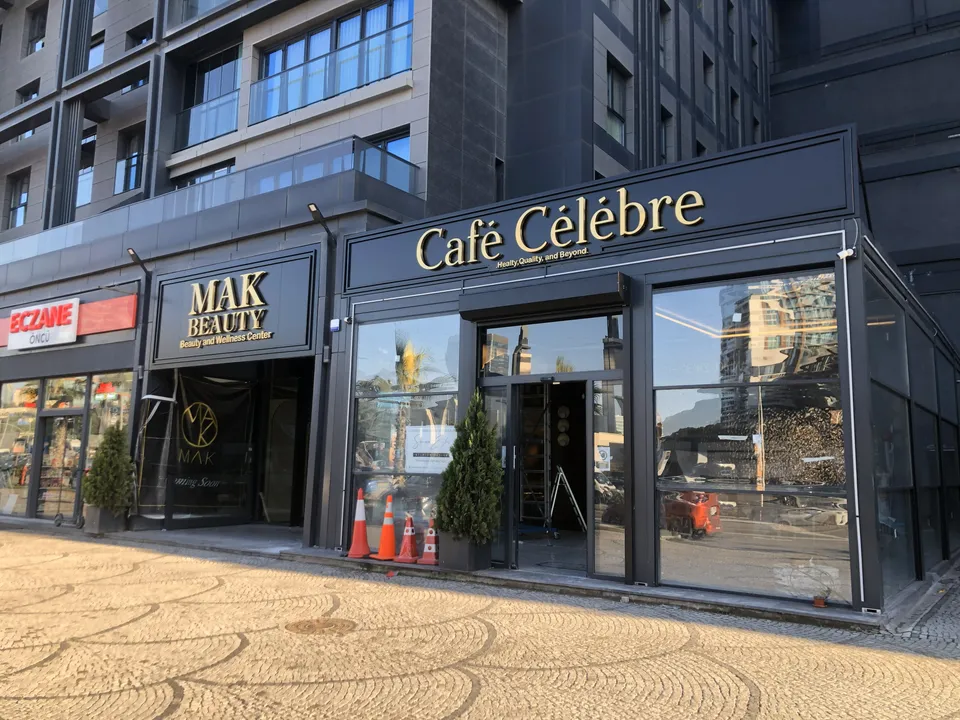 Café Célèbre altın cephe harfleri ve vitrin uygulaması, kaldırımdan görünüm.