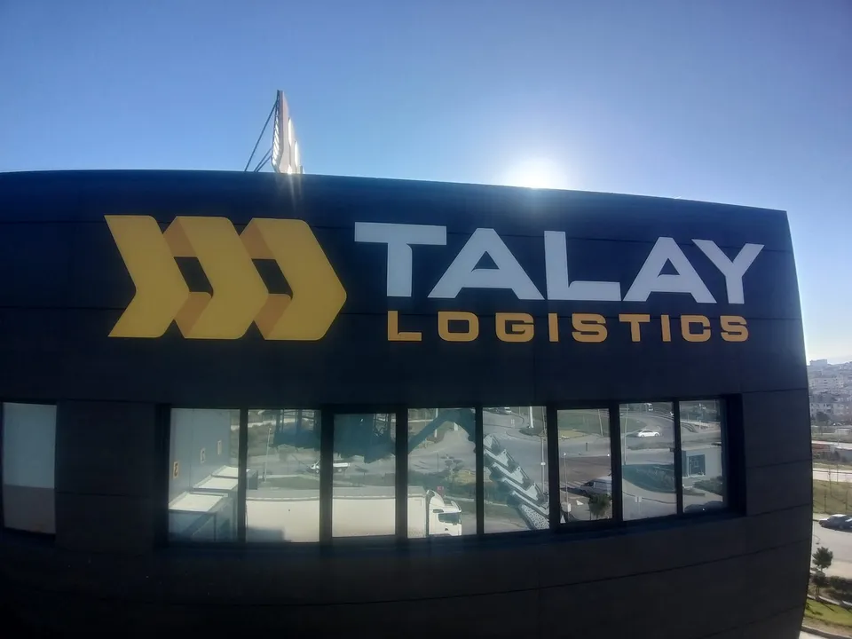 Talay Logistics cephe tabelası, koyu kompozit yüzeyde yakın gündüz görünümü.