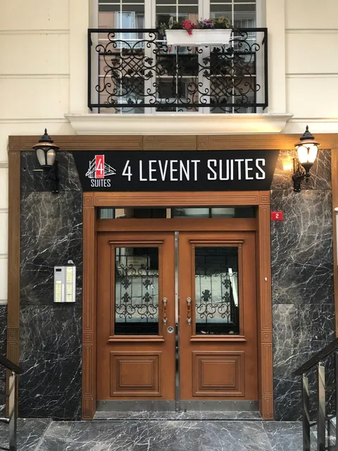 4 Levent Suites binasının mermer ve ahşap girişinde siyah panel üzerine beyaz harfli ve kırmızı 4 logolu tabela, karşıdan görünüm.