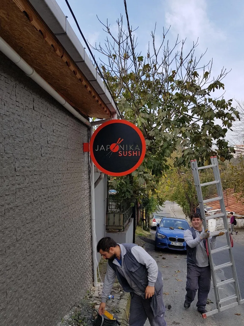 Siyah-kırmızı yuvarlak fener tabelanın dış cepheye montajı.