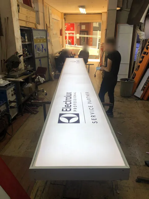Electrolux Professional Service Partner yazılı uzun beyaz ışıklı kutu tabelanın atölyede üretim aşaması, yukarıdan boylamasına görünüm.