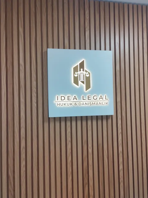 Idea Legal Hukuk ve Danışmanlık için çıtalı ahşap duvarda mavi panoda arkadan ışıklı logo ve harfler, karşıdan görünüm.