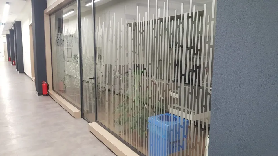 Cam ofis duvarlarında geometrik dikey desenli kumlama folyosu.