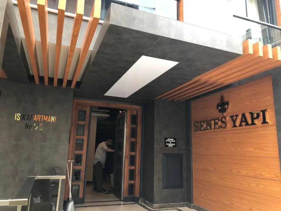 Senes Yapı bina girişinde ahşap çıta, metal sundurma ve kabartma harf uygulaması.