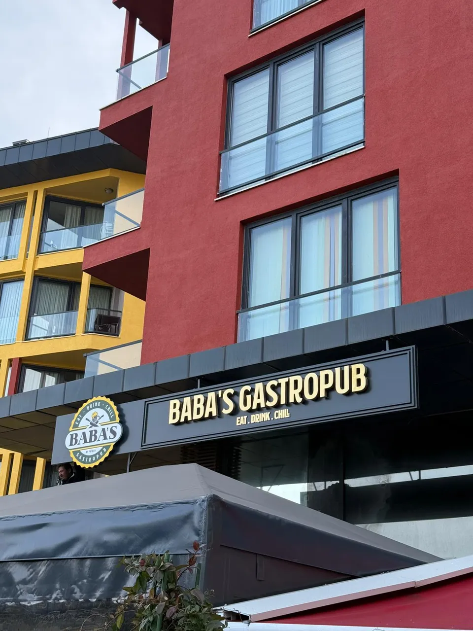 Baba’s Gastropub için siyah alınlıkta altın paslanmaz harf ve yuvarlak logolar.