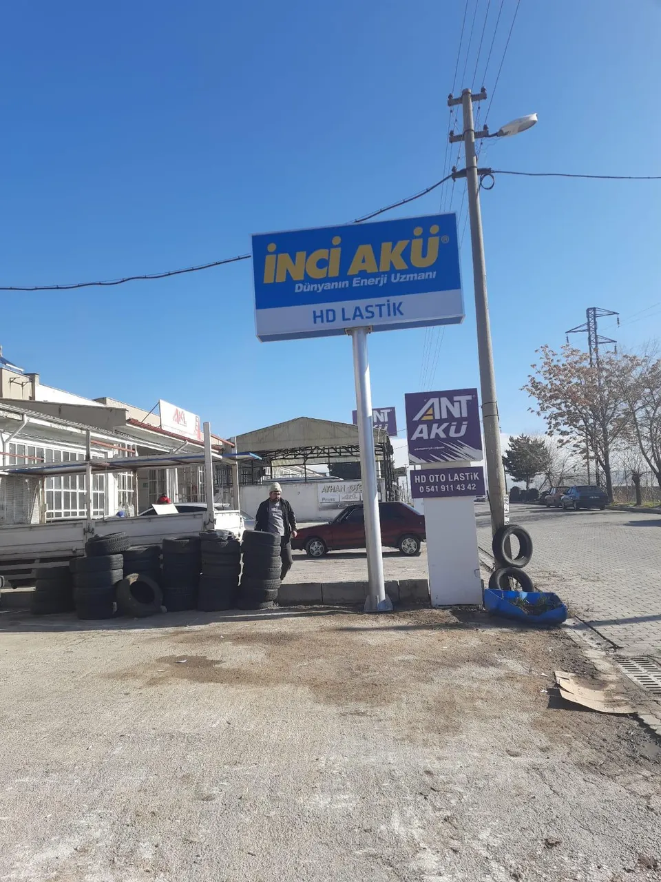 İnci Akü mavi-sarı yol kenarı totem tabelası, servis alanı görünümü.