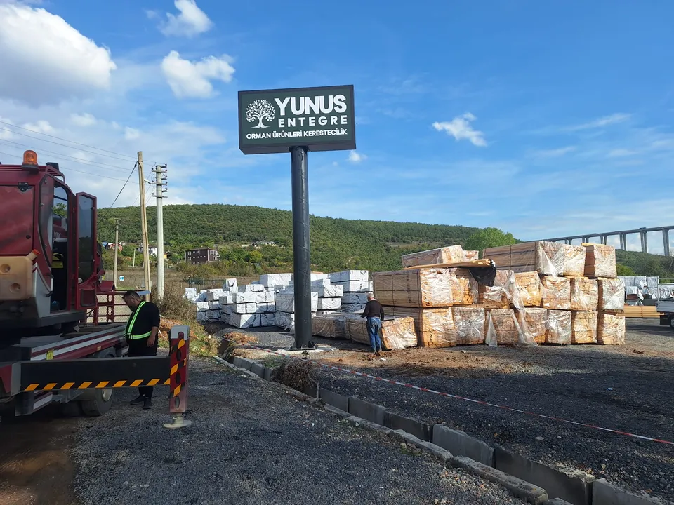 Yunus Entegre siyah-beyaz totem tabelası, endüstriyel depolama sahası görünümü.